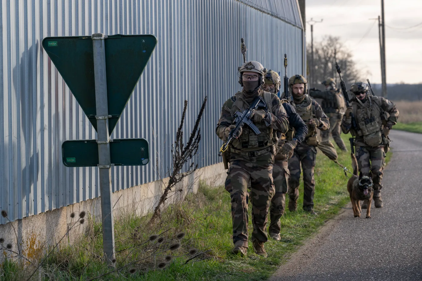 Patrouille de militaires français avec chien d'assaut le long d'un hangar pendant la phase 4 d'ORION 2026